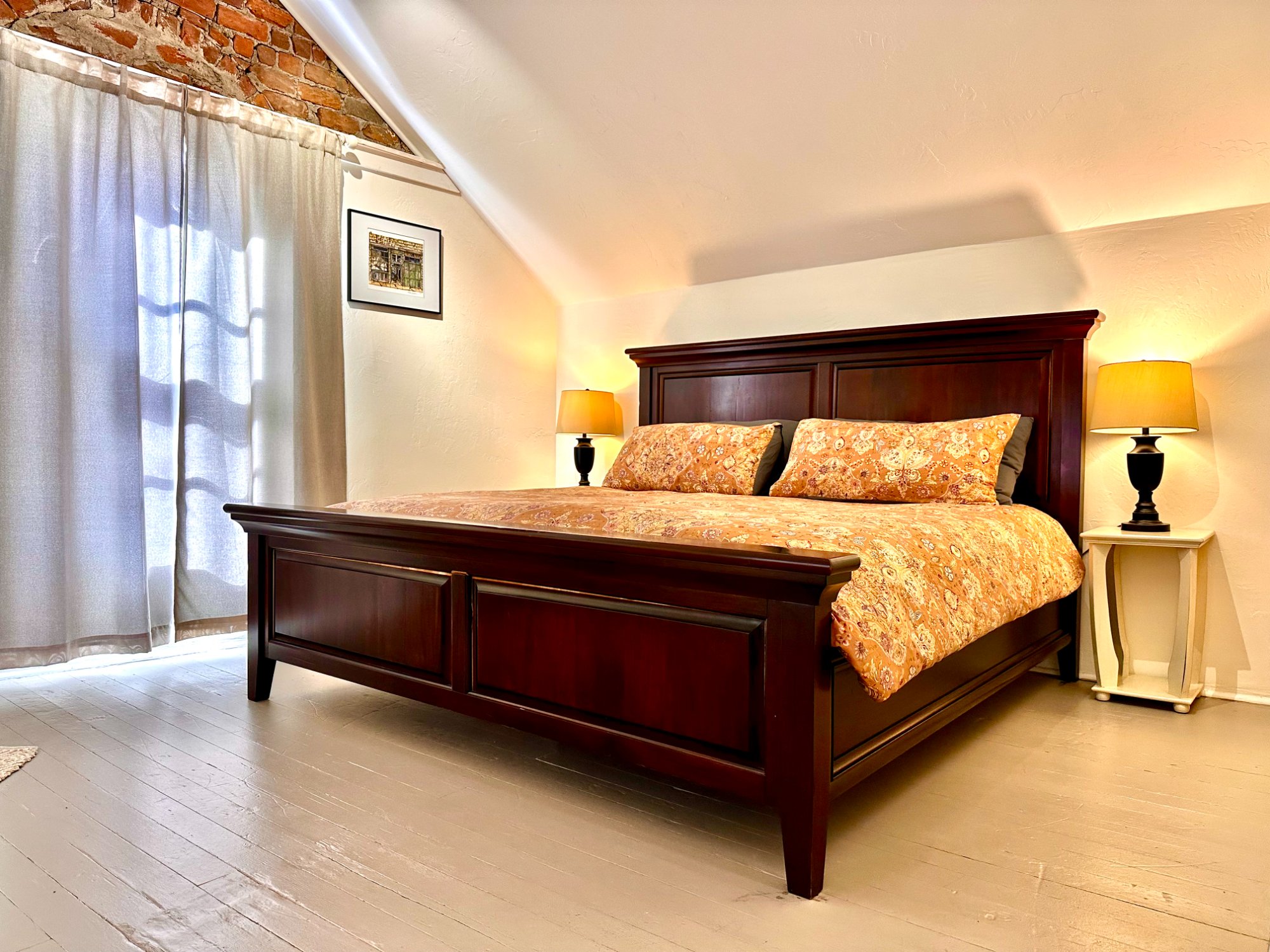 King bed with exposed 1800s brick gable behind